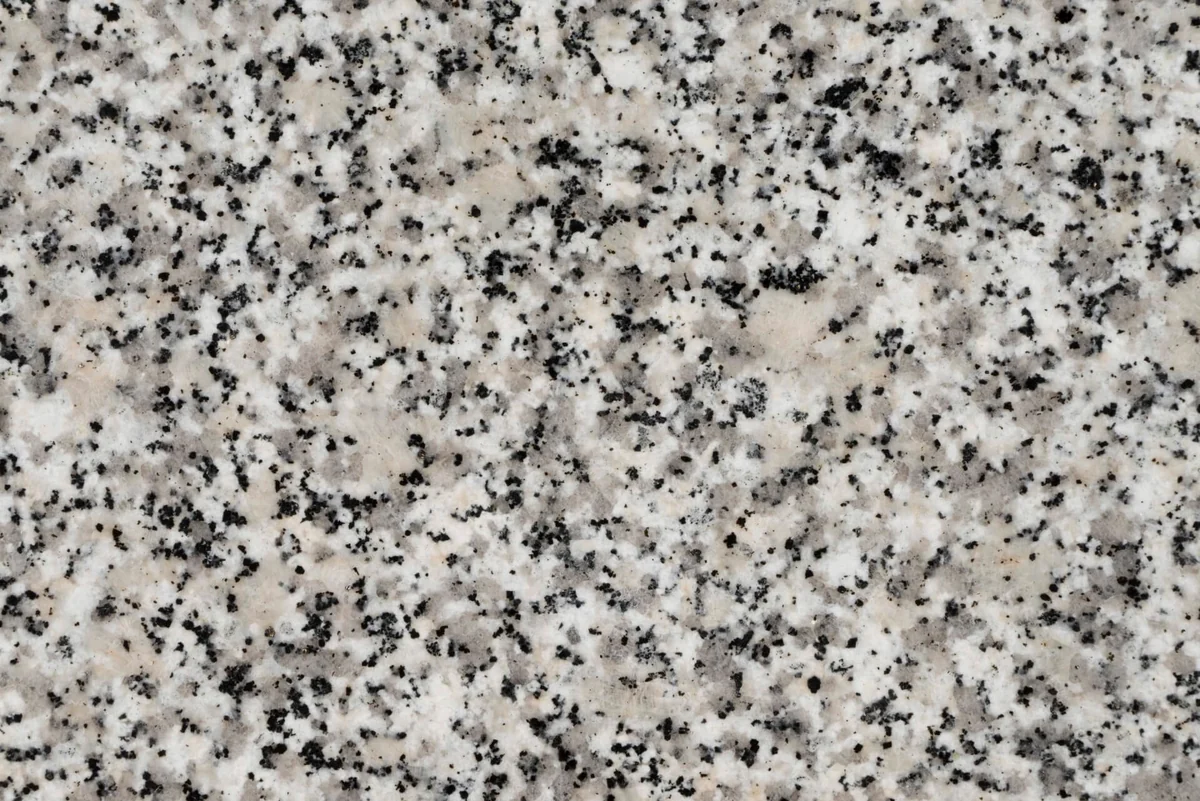 Textura de granito claro con manchas negras y grises